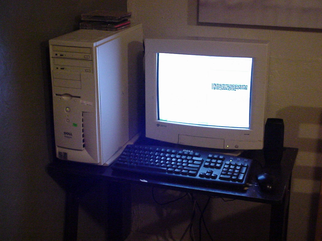 photo of the dell dimension 4100 set up at a small desk next to my bed. the dynamic range of the camera is crap and you can hardly see anything